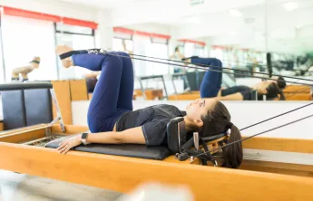 woman using pilates reformer