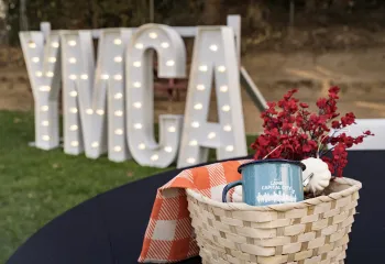 YMCA lighted letters in the background, with a basket and a YMCA mug in it