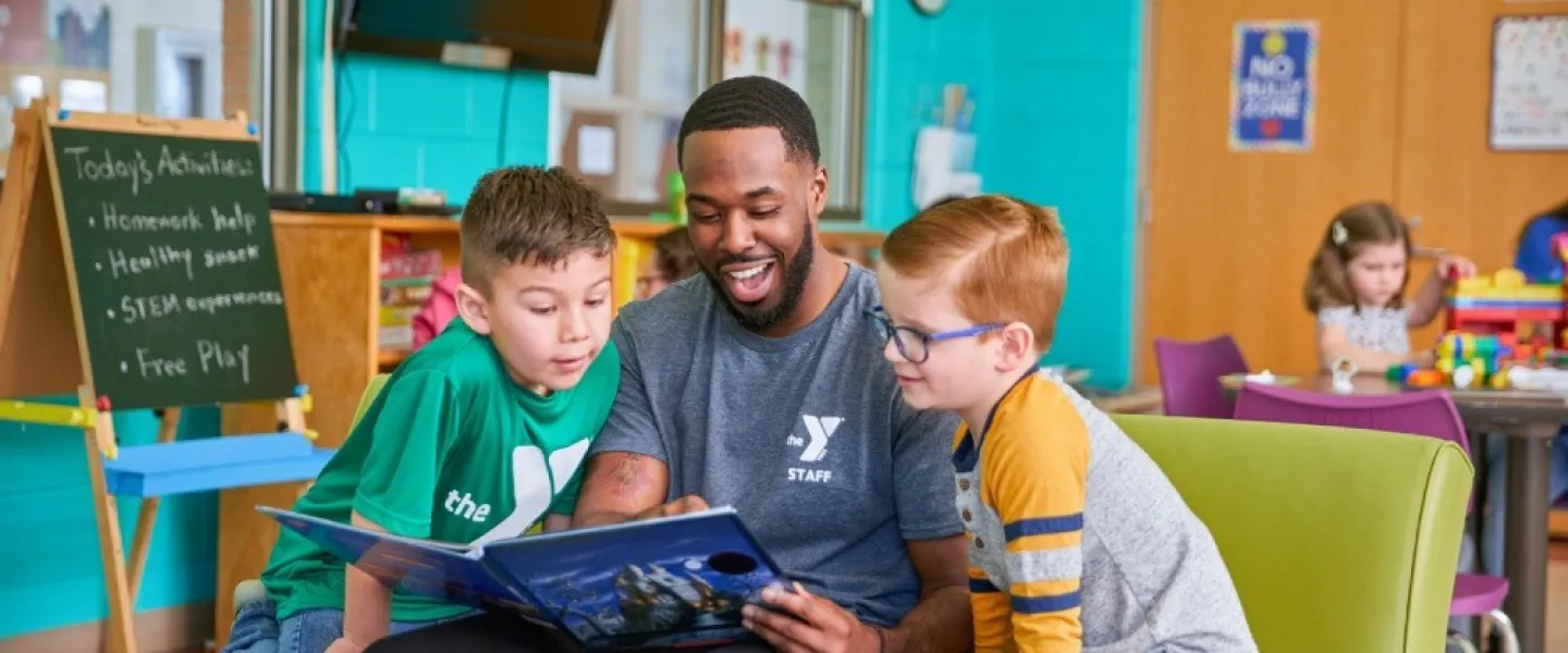 YMCA employee reading to two students