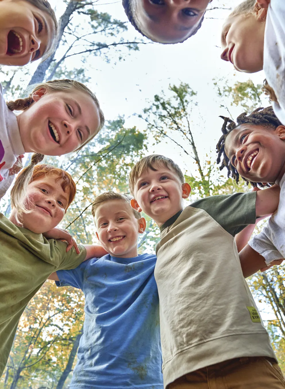 Kids on each others shoulders in a circle in the woods