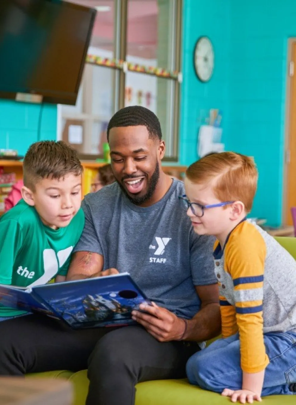 YMCA employee reading to two students