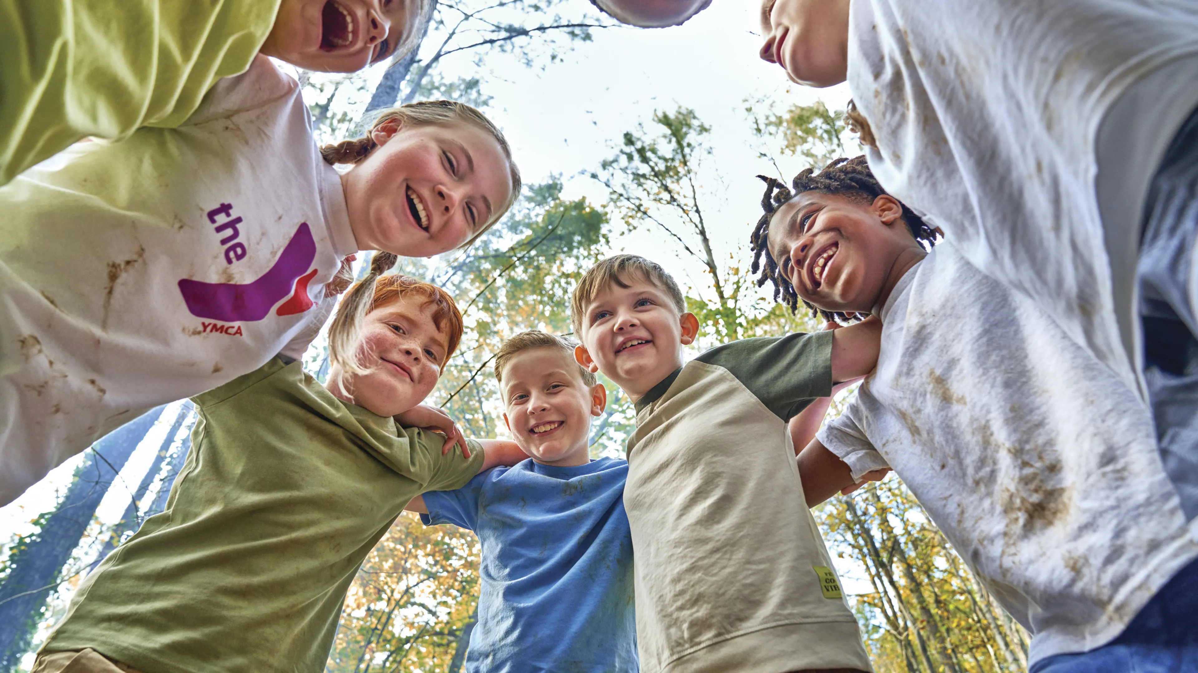 Kids on each others shoulders in a circle in the woods