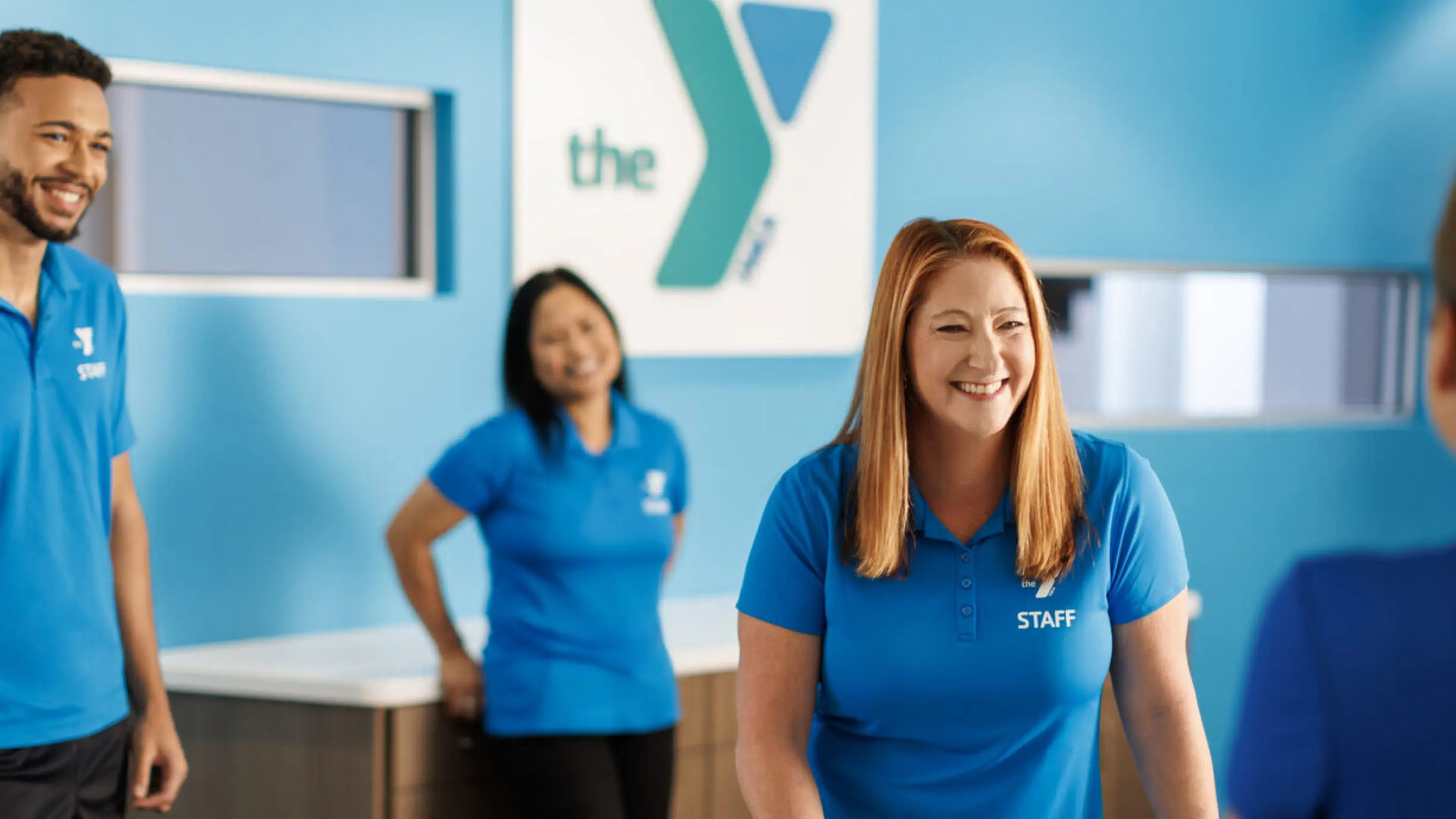 workers standig behind desk facing customer, ymca sign in background