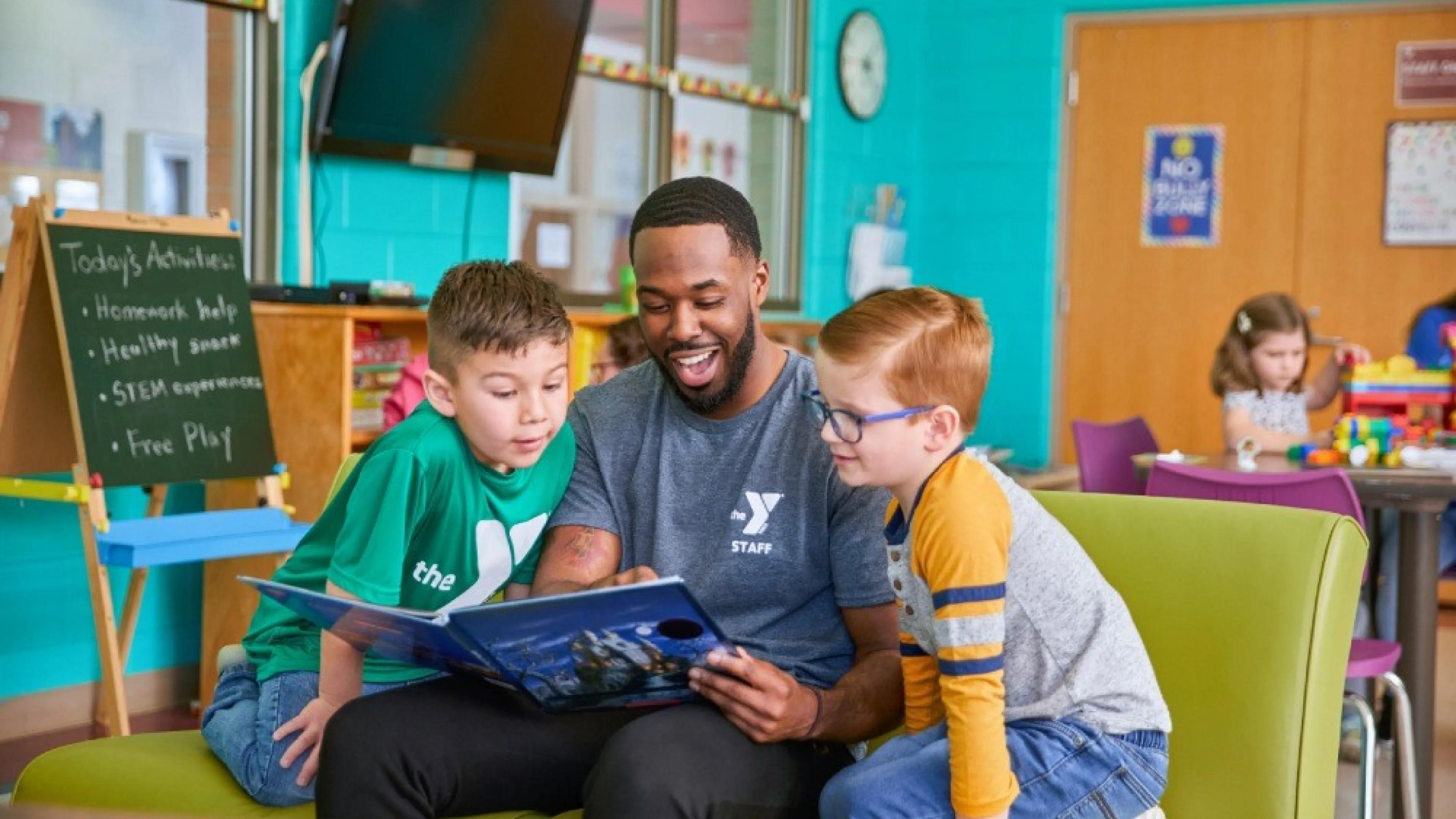YMCA employee reading to two students