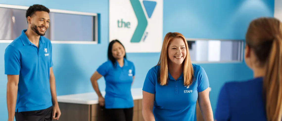 workers standig behind desk facing customer, ymca sign in background