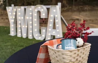 YMCA lighted letters in the background, with a basket and a YMCA mug in it
